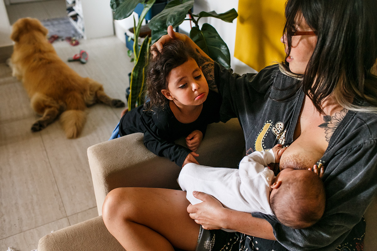 foto de Adriana Costa da menina chamando a atenção da mãe que está amamentando seu irmão