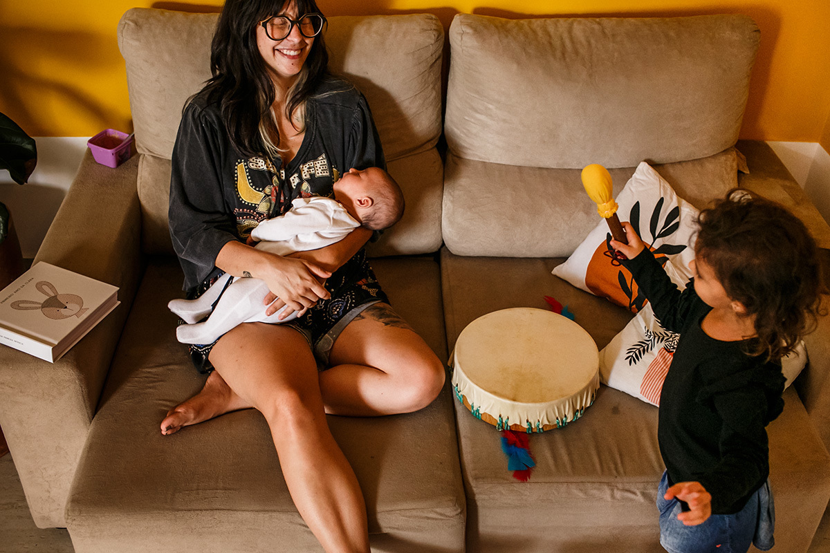 mãe com bebê recém-nascido brinca com a filha mais velha alegremente