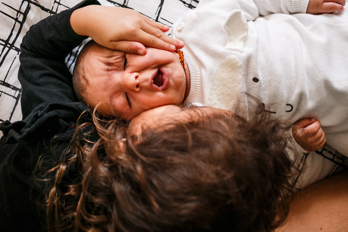 menina amassa seu irmão bebê ao lhe dar um beijo em foto de Adriana Costa