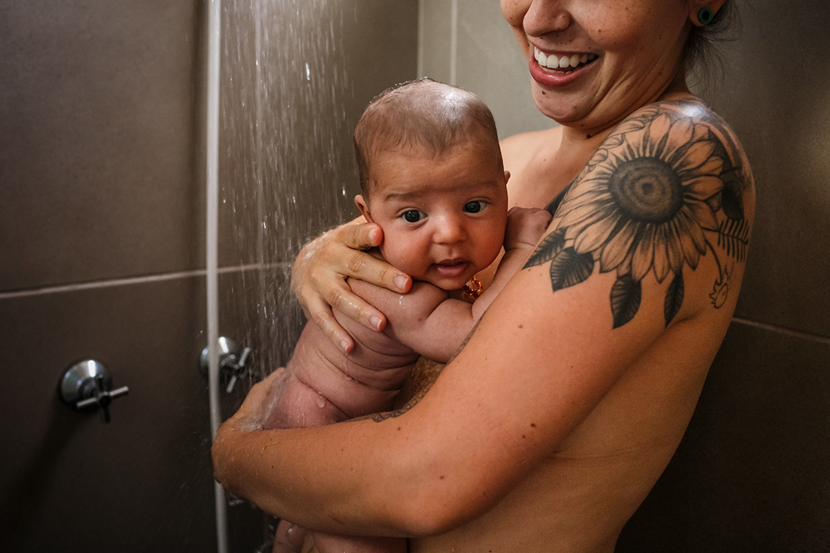 mãe tomando banho de chuveiro com seu bebê
