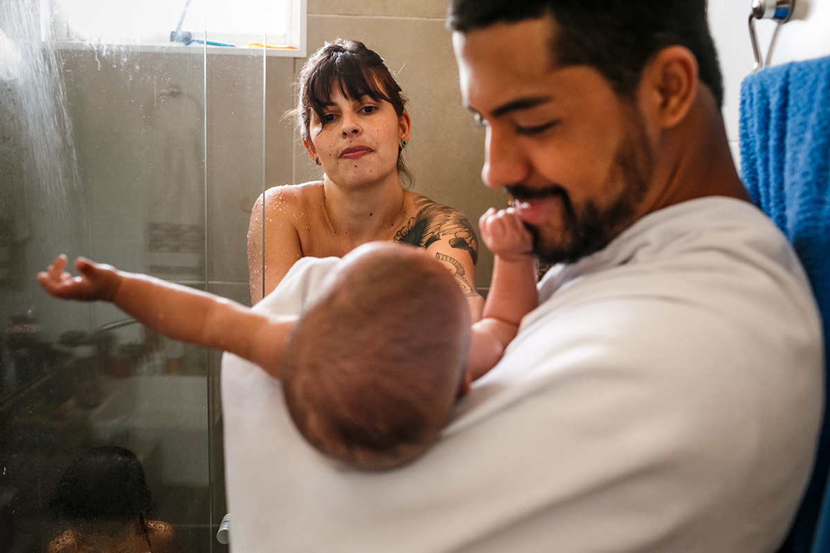 pai pega o bebê no banho para trocar sua roupa