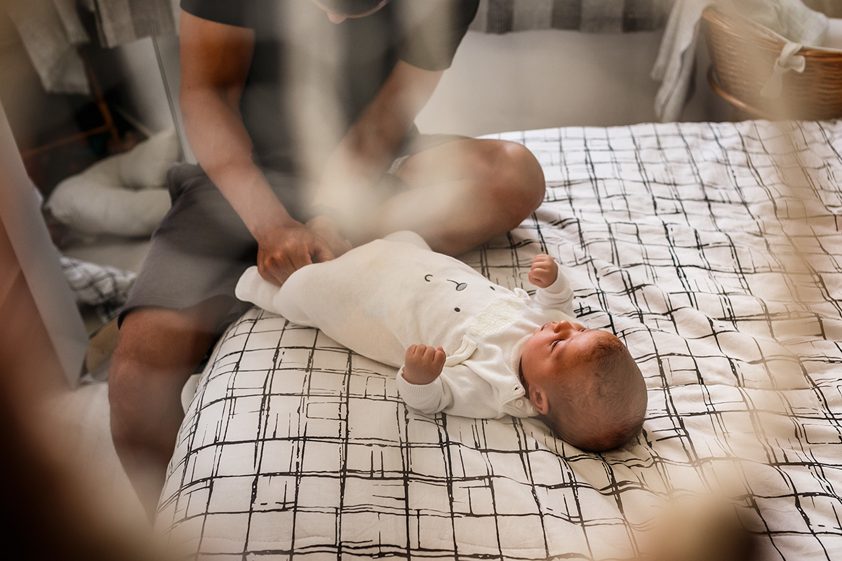 pai troca a roupa do seu bebê