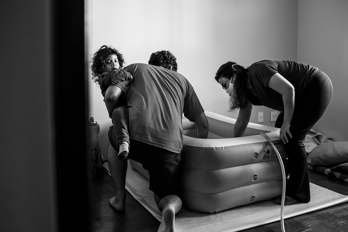 família enchendo a banheira para um parto domiciliar
