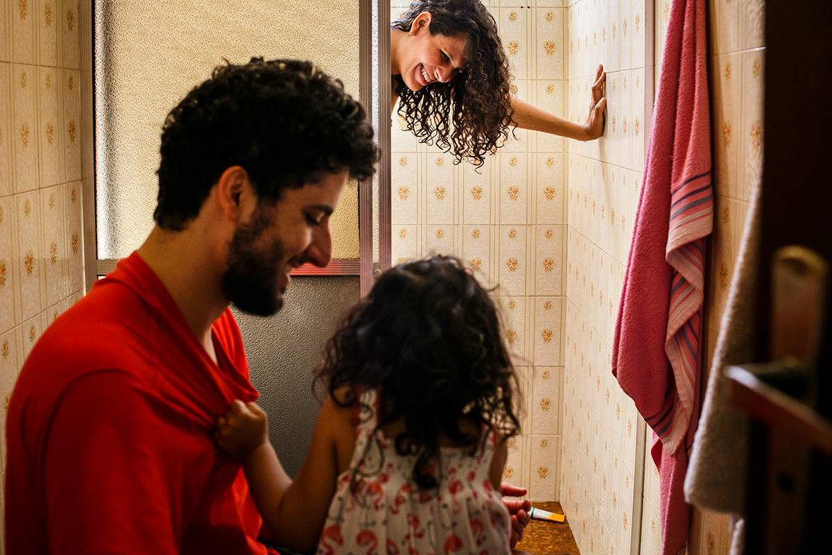 marido e filha observam a mulher no chuveiro para aliviar as dores das contrações durante o trabalho de parto