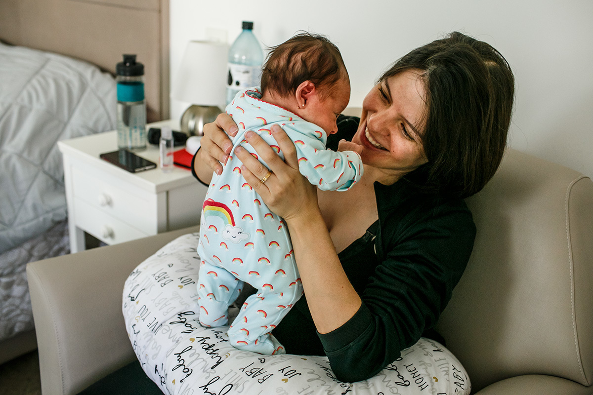 mãe pegando feliz sua bebê para amamentar