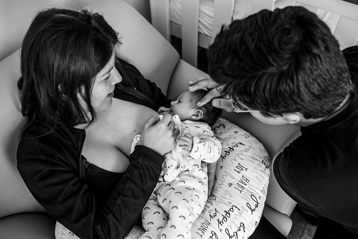 pai faz carinho na sua bebê recém-nascida enquanto ela amamenta