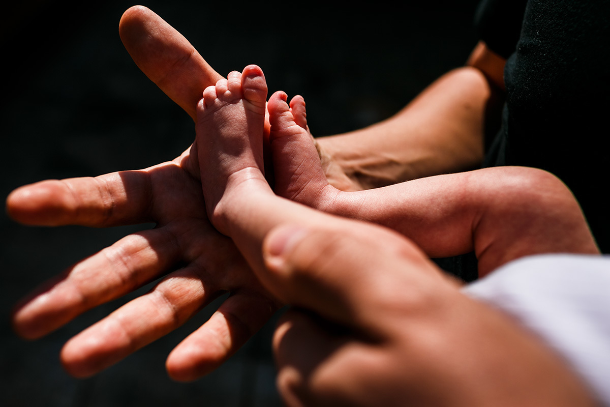 pai segura pés do seu bebê recém-nascido ao sol para receber vitamina D