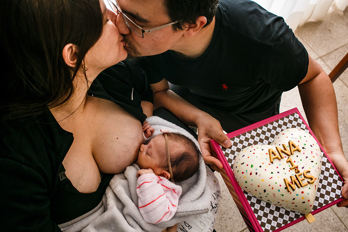 pais comemoram com um bolo de coração o primeiro mês de sua bebê