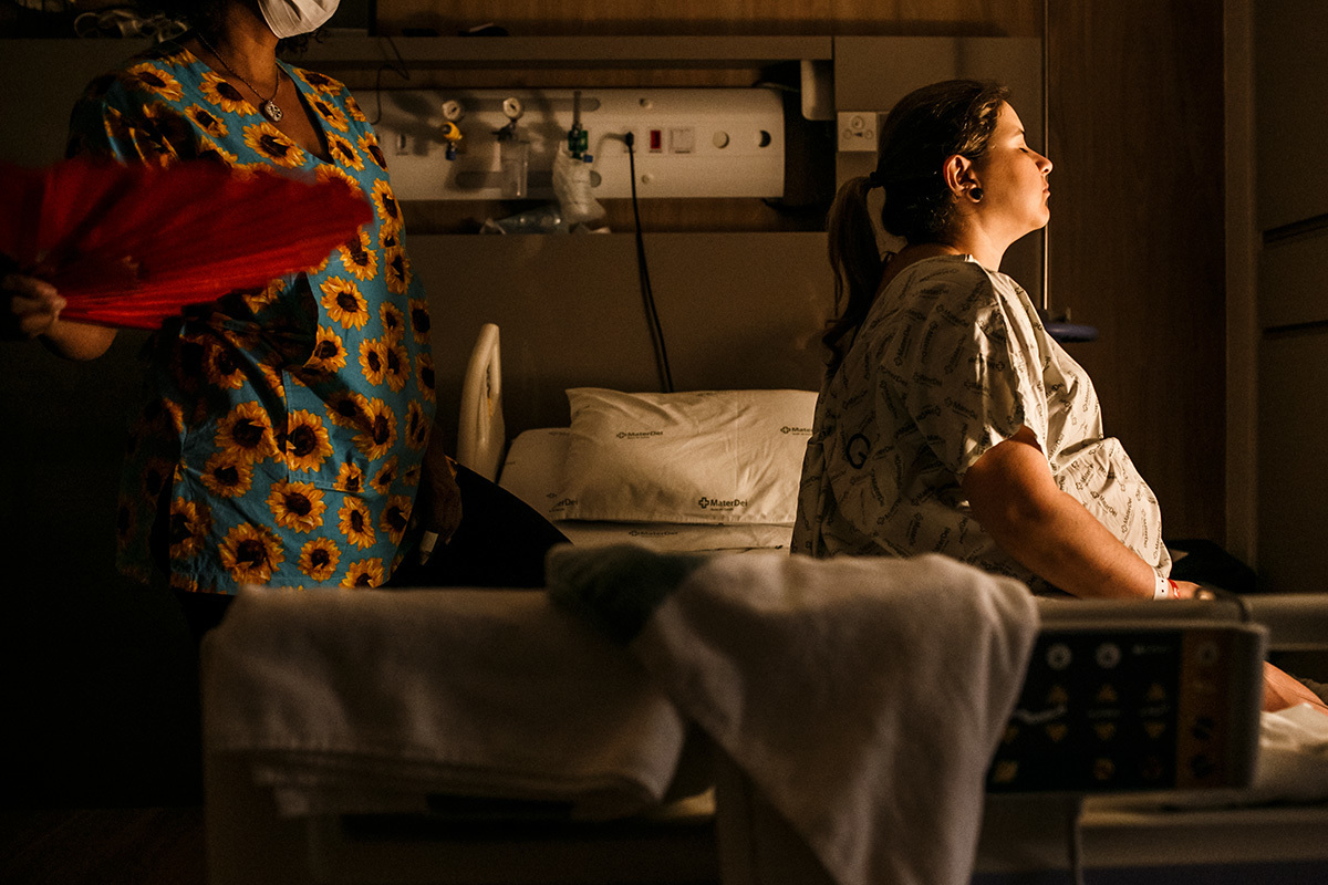 mulher sendo ventilada pela doula com um leque durante seu trabalho de parto