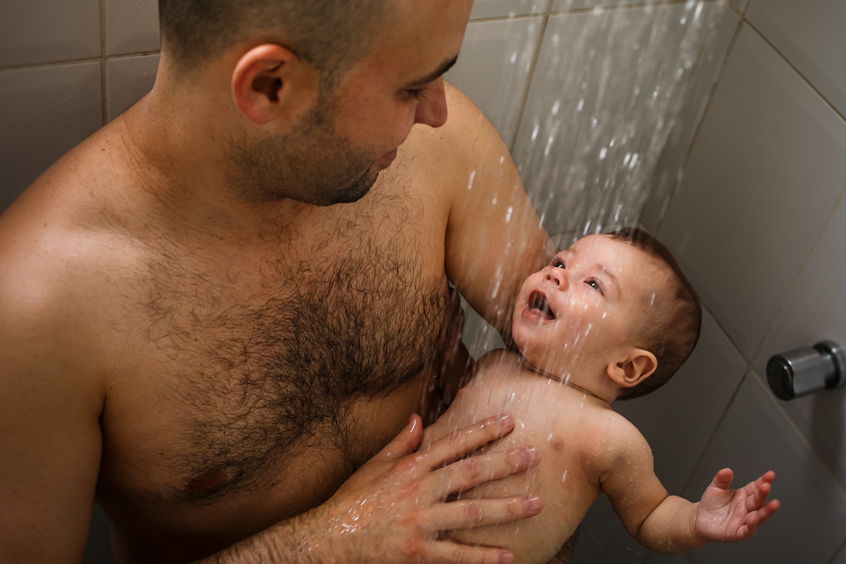 bebê de 6 meses tomando banho de chuveiro com o pai em foto de Adriana Costa