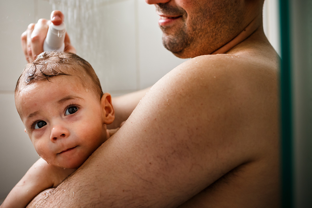 pai passando xampu no seu bebê durante banho de chuveiro