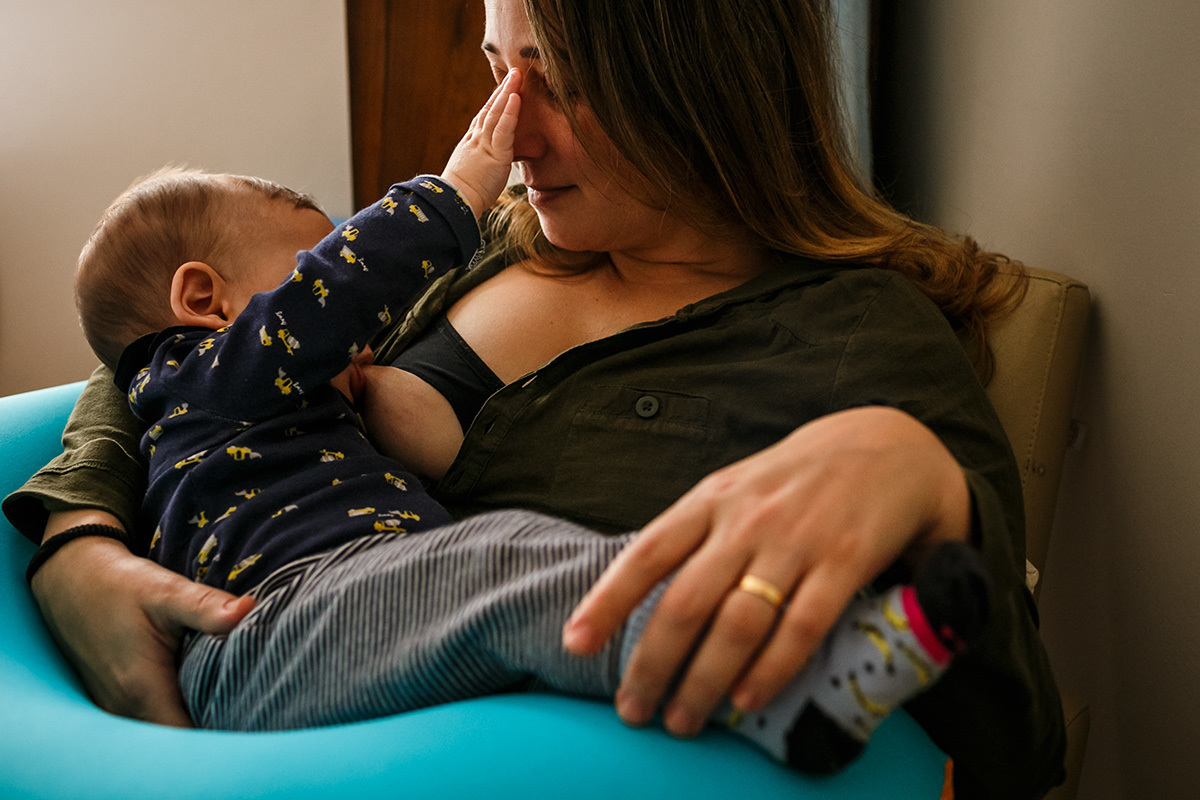 bebê fazendo carinho na mãe durante a amamentação
