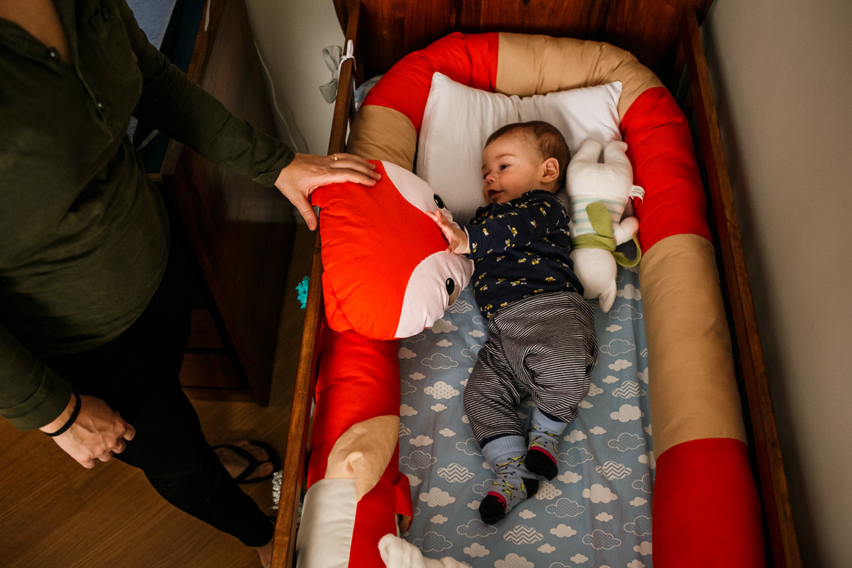 mãe brinca com seu bebê no berço