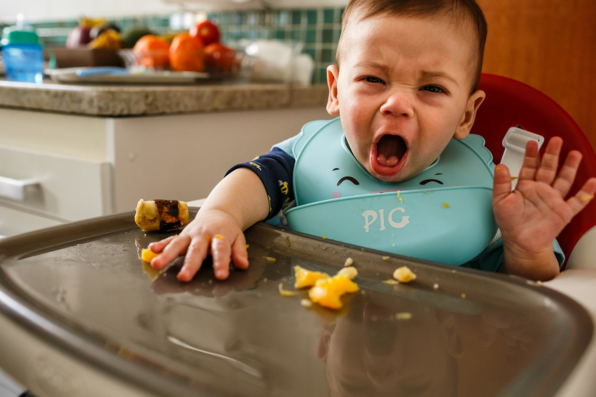 bebê fazendo careta ao comer fruta