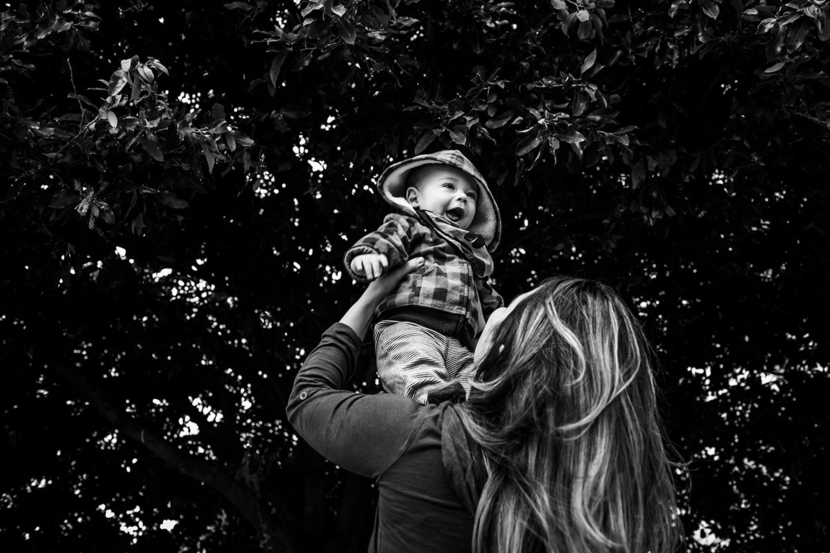 mãe brinca com seu bebê de 6 meses sob uma grande árvore