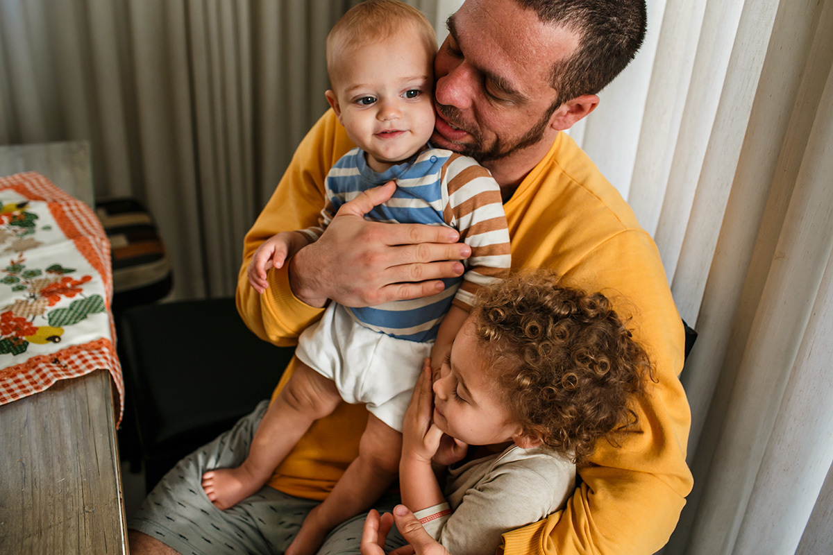 pai e filhos em momento de carinho em foto de Adriana Costa