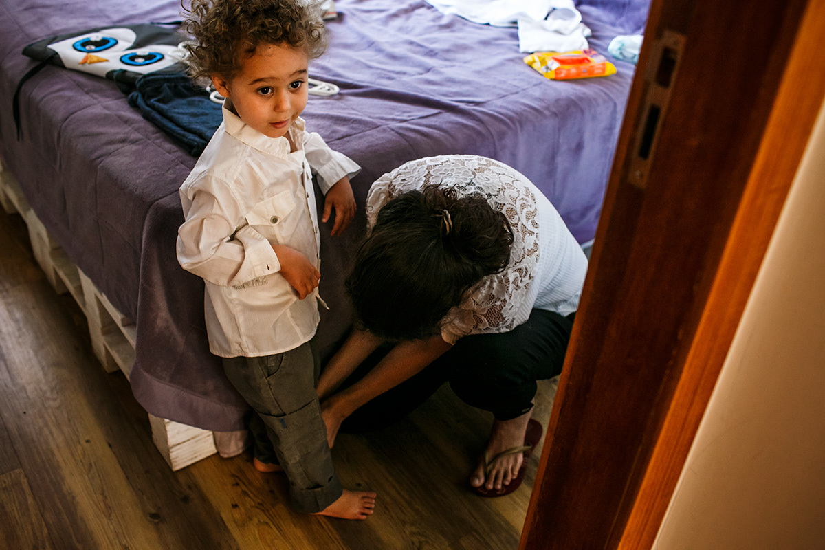 mãe arrumando seu filho mais velho para o batizado do caçula