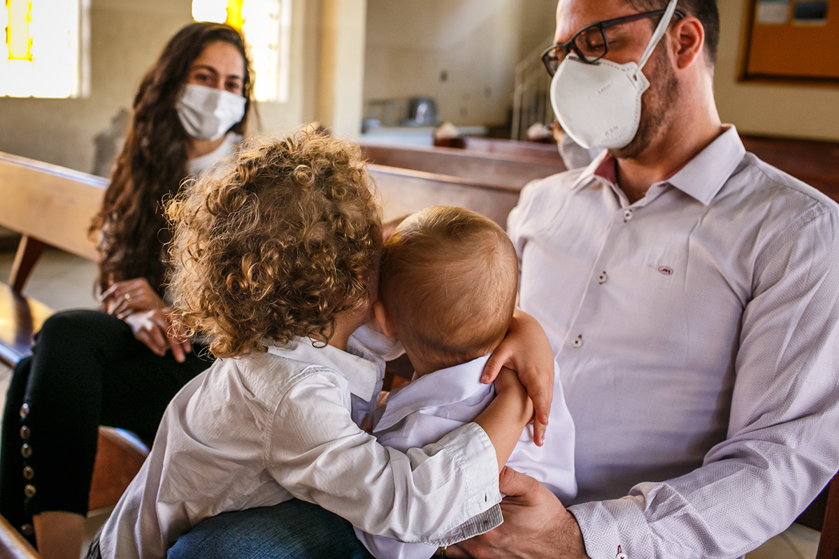irmãos se abraçam carinhosamente durante o batizado