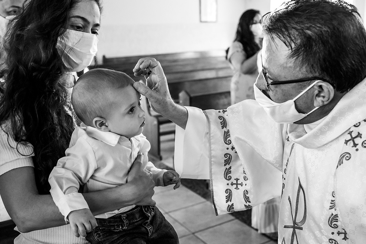 padre faz o sinal da cruz dando a benção no bebê na missa de batismo