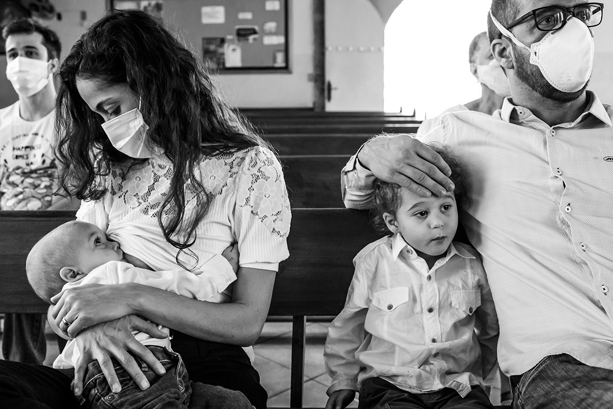 mãe amamenta seu bebê durante a missa de batismo