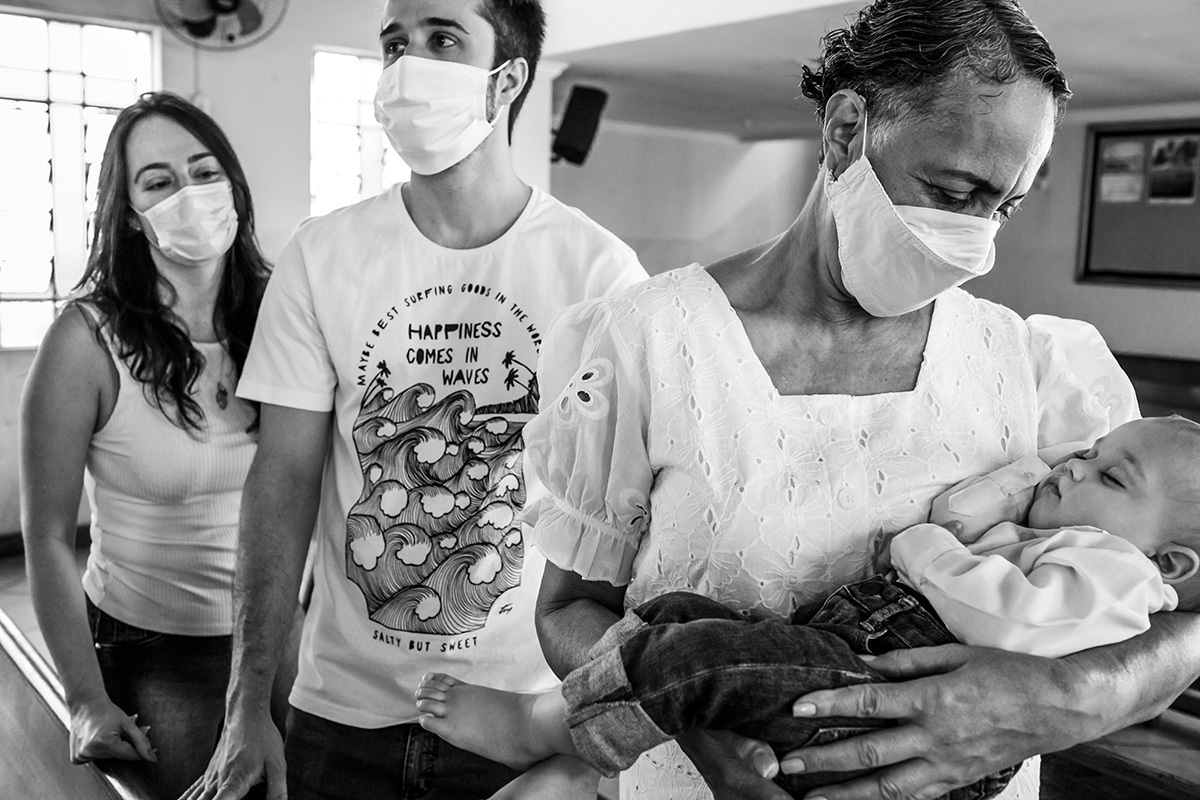 bebê dorme nos braços da madrinha durante o seu batizado