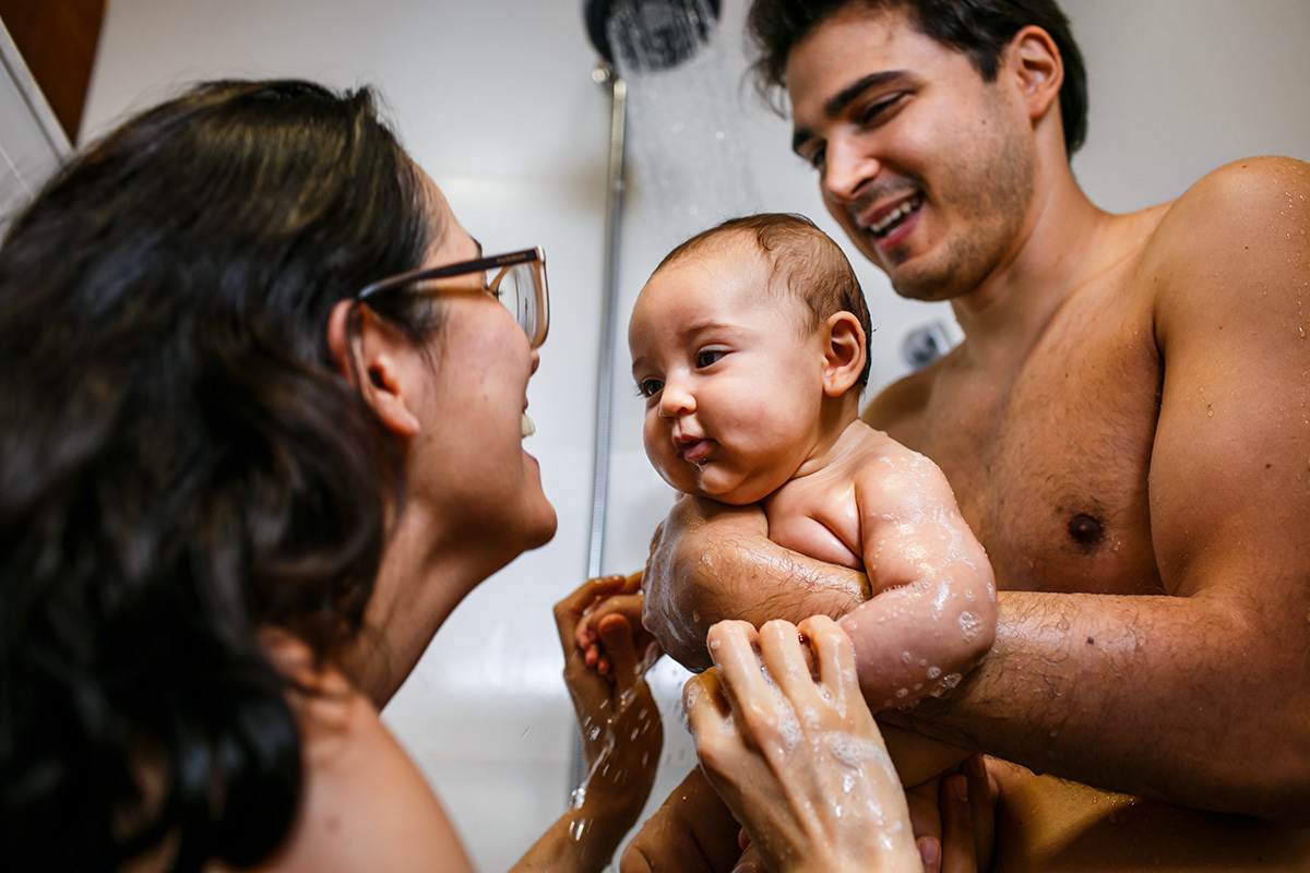 casal dando banho de chuveiro na sua bebê em foto de Adriana Costa
