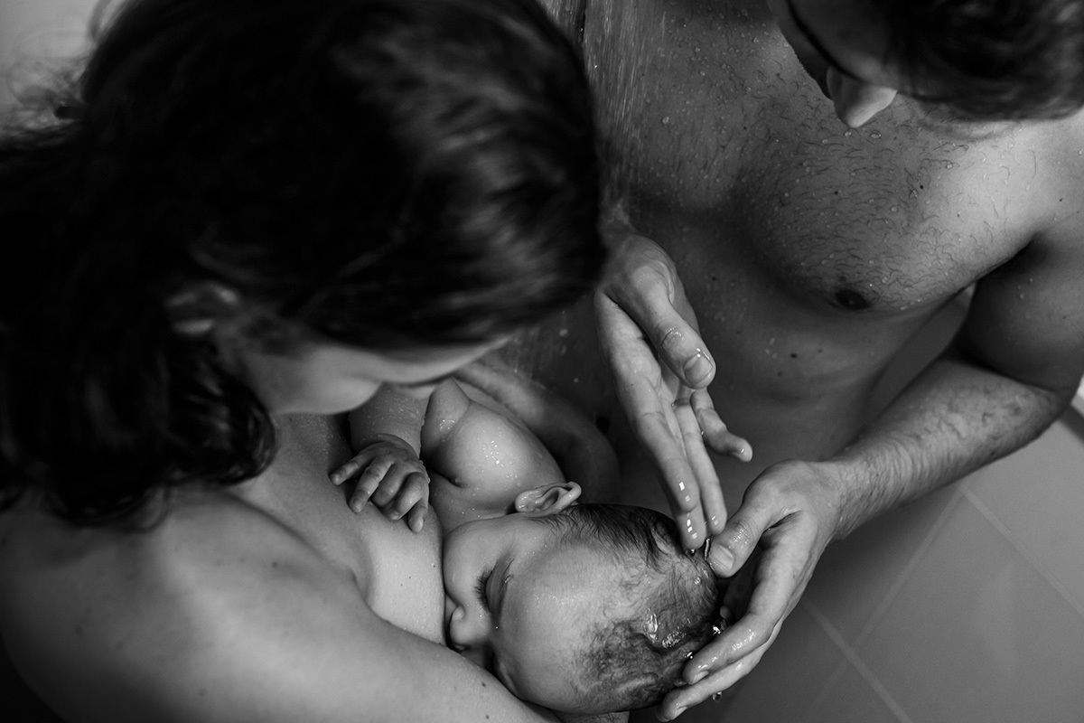 bebê amamenta no banho com seus pais