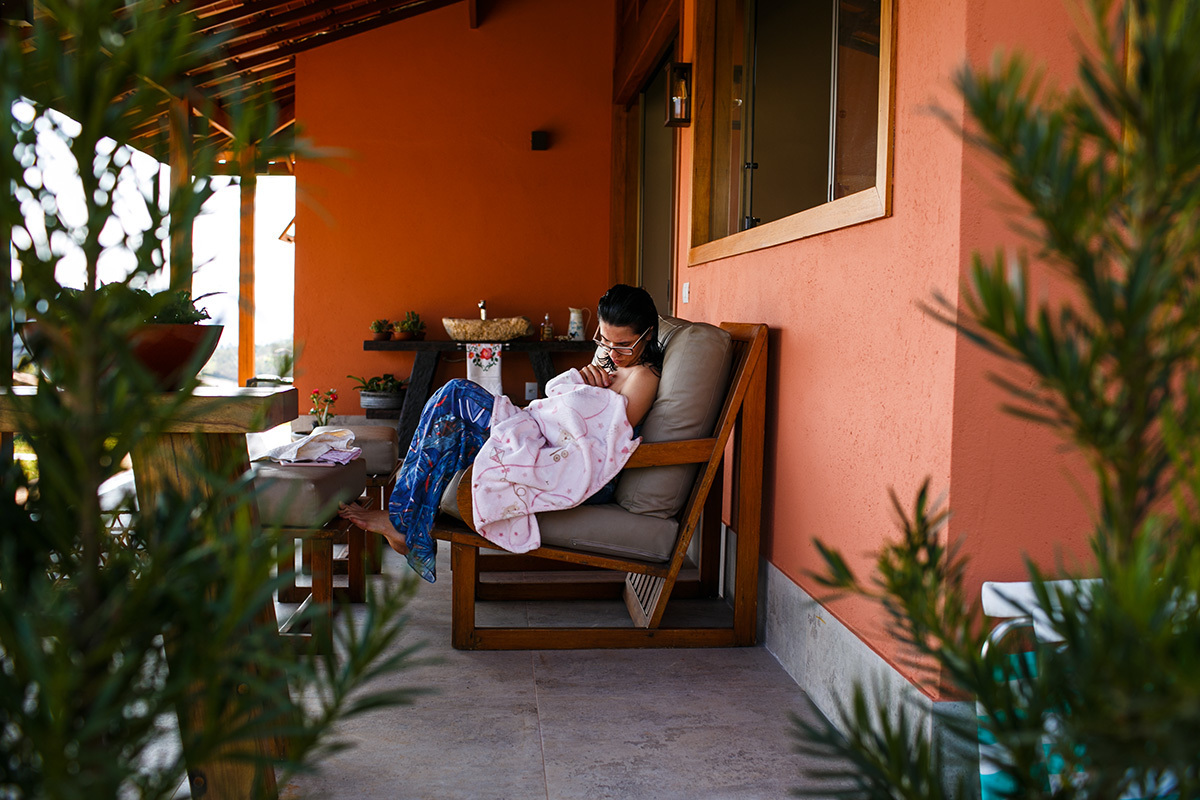 mãe amamentando na varanda da casa no dia do batismo