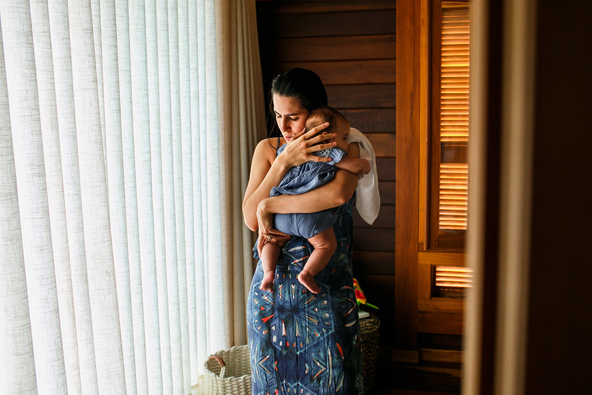 mãe ninando sua bebê para dormir no dia do batismo com enterro da placenta em foto de Adriana Costa