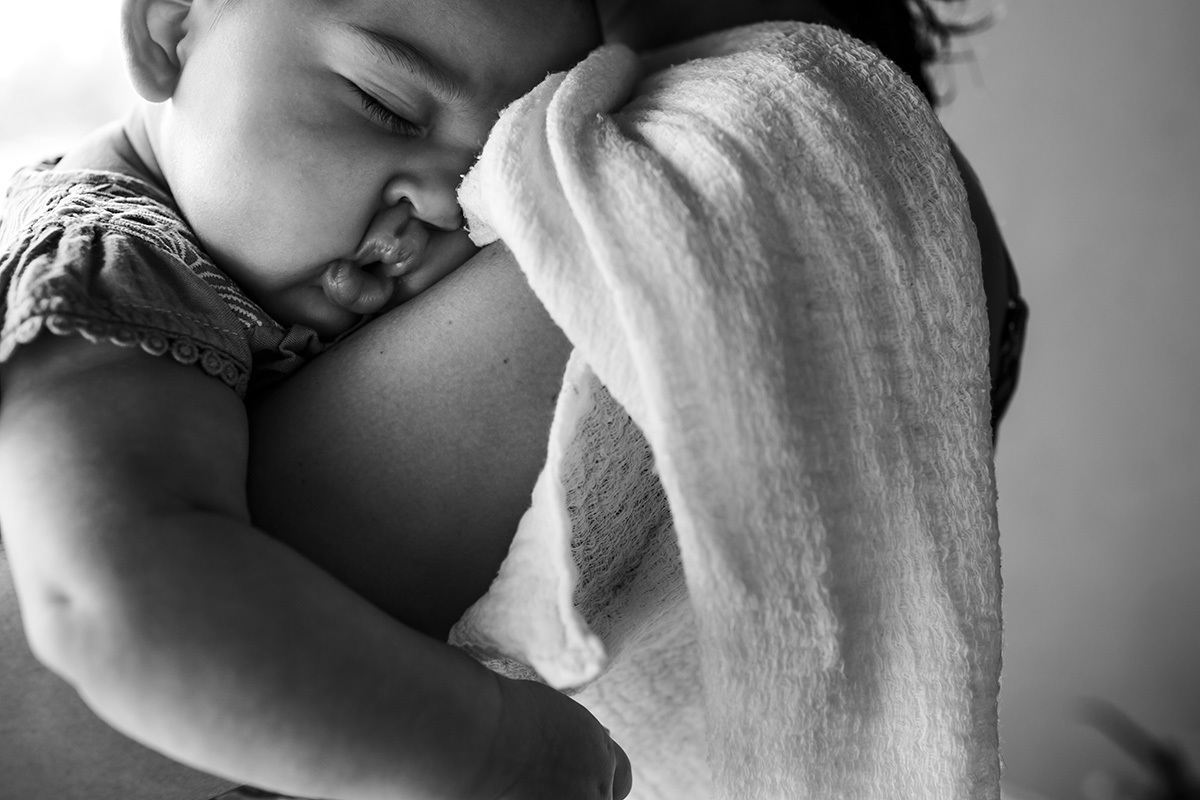 bebê dormindo relaxada no colo da mãe em foto de Adriana Costa