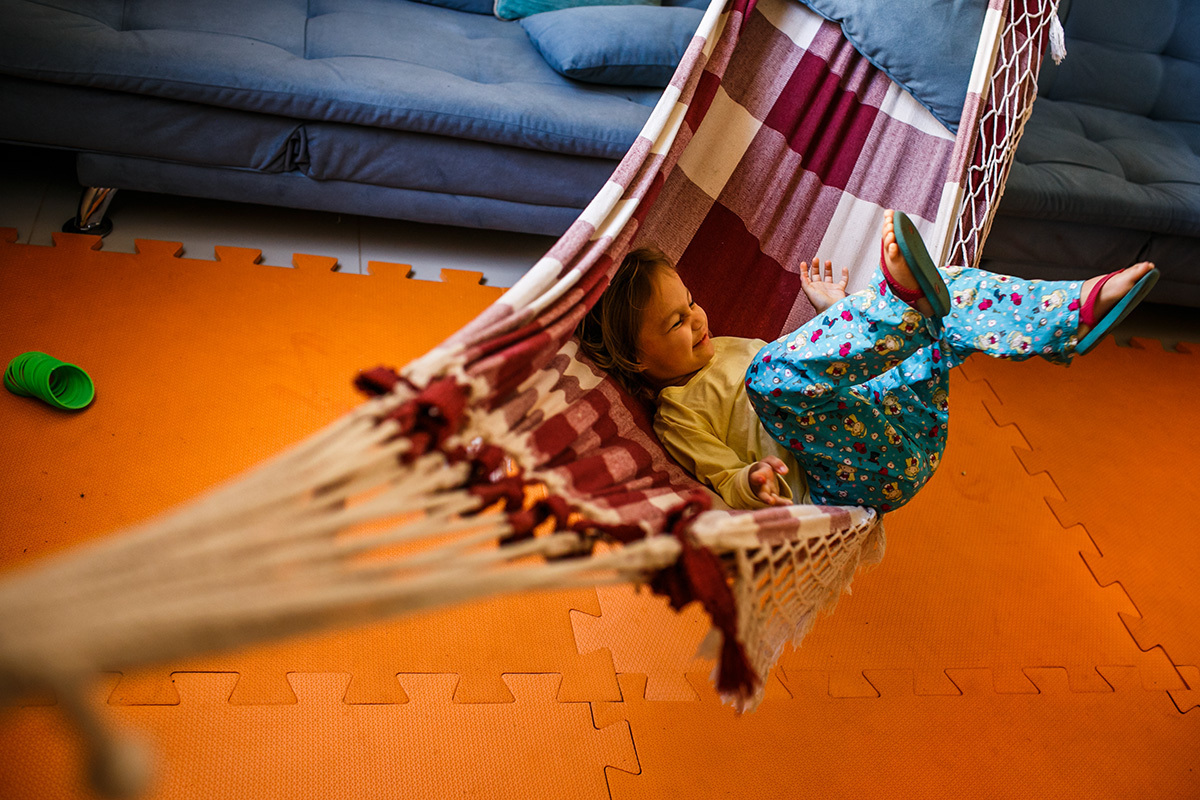 menina se diverte balançando na rede da sua casa