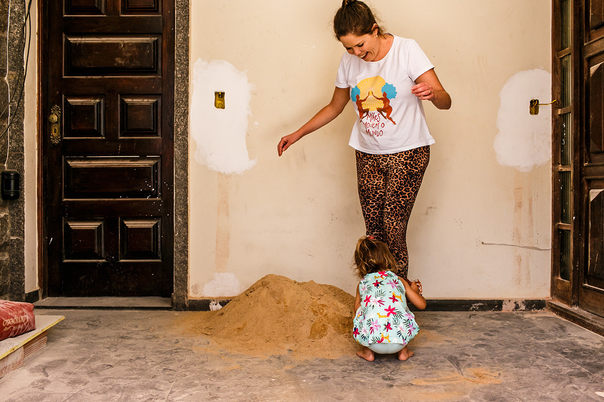 Criança brinca de areia na sua casa que está em reforma