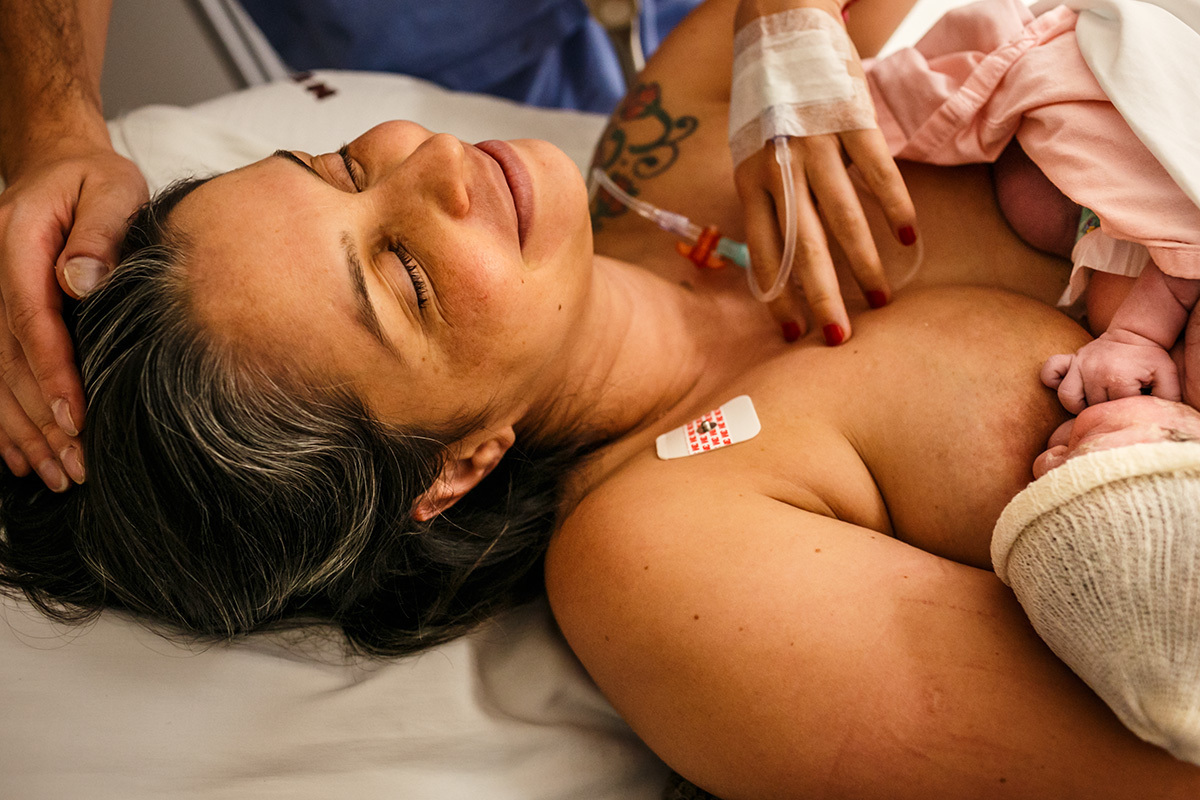 mãe se tranquiliza após o nascimento da filha de uma cesárea devido ao diagnóstico de vasa prévia em foto de Adriana Costa