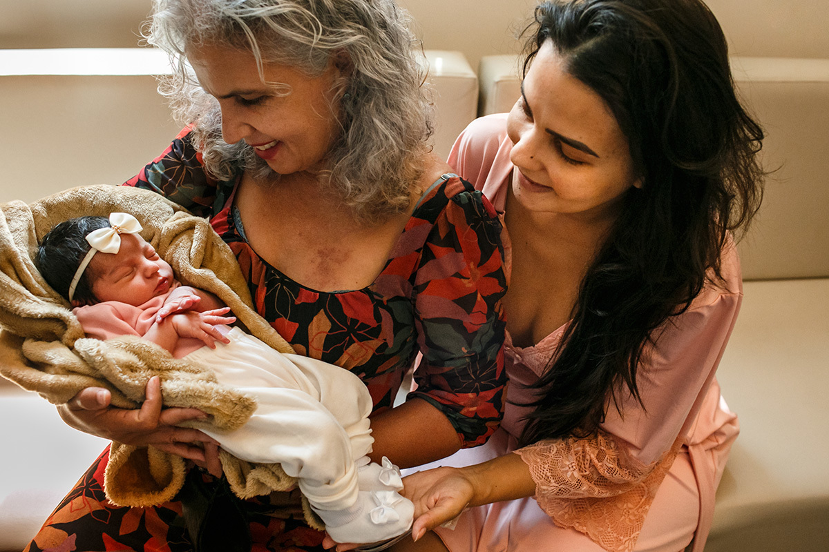 avó e mãe admiram a bebê que acabou de nascer