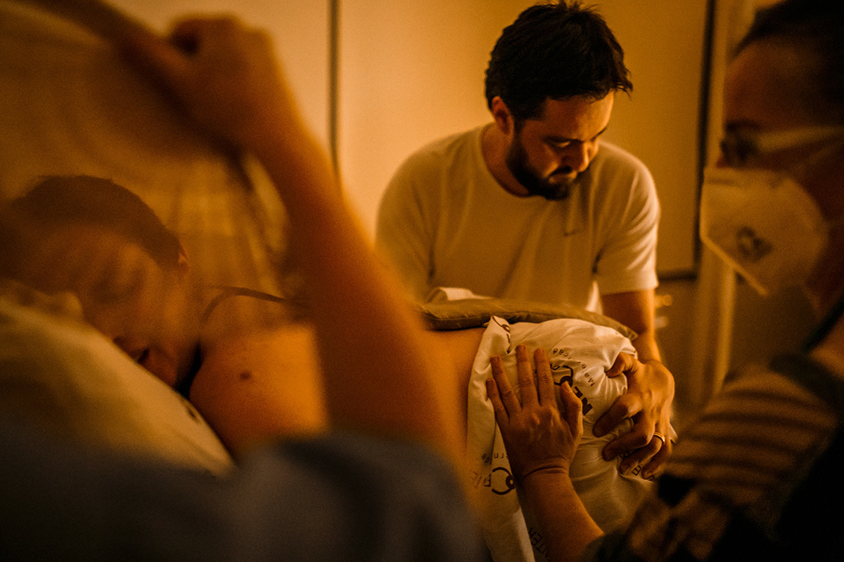 marido ajuda a comprimir as laterais do quadril da sua esposa para aliviar as dores das contrações do trabalho de parto