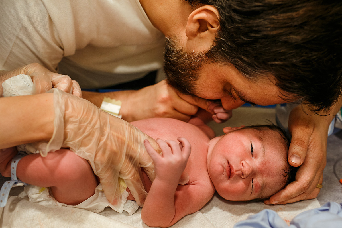 pai beija e conta histórias ao seu bebê após o nascimento durante os primeiros exames pela pediatra
