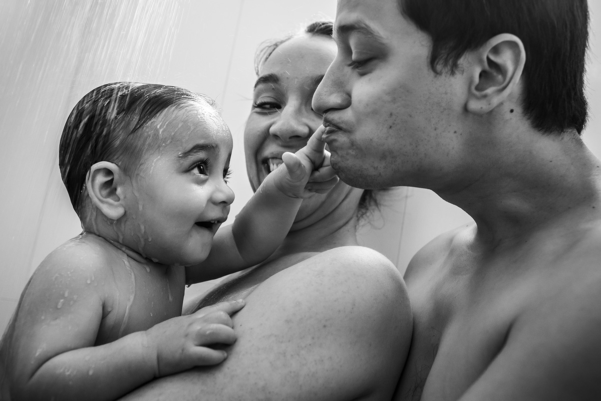 pais dando banho de chuveiro no seu bebê de 1 ano