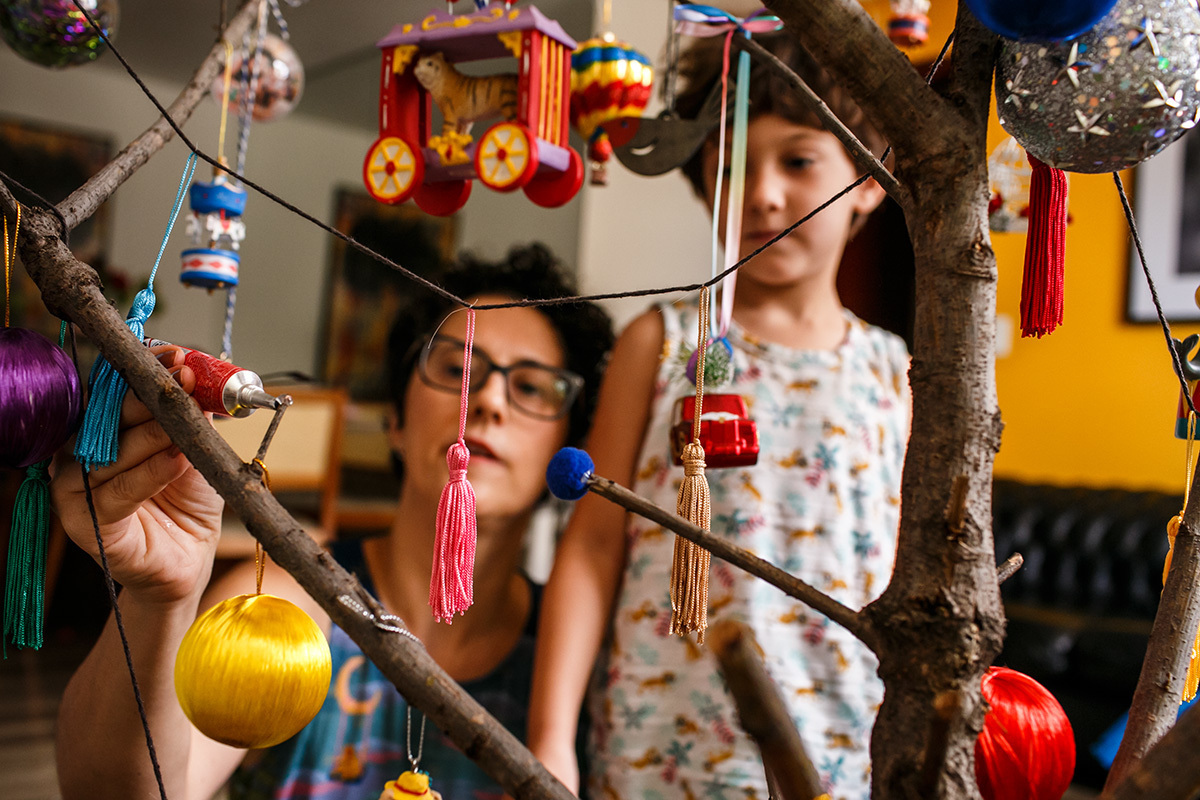 mãe e filho colam bolinhas de feltro coloridas em sua árvore de natal