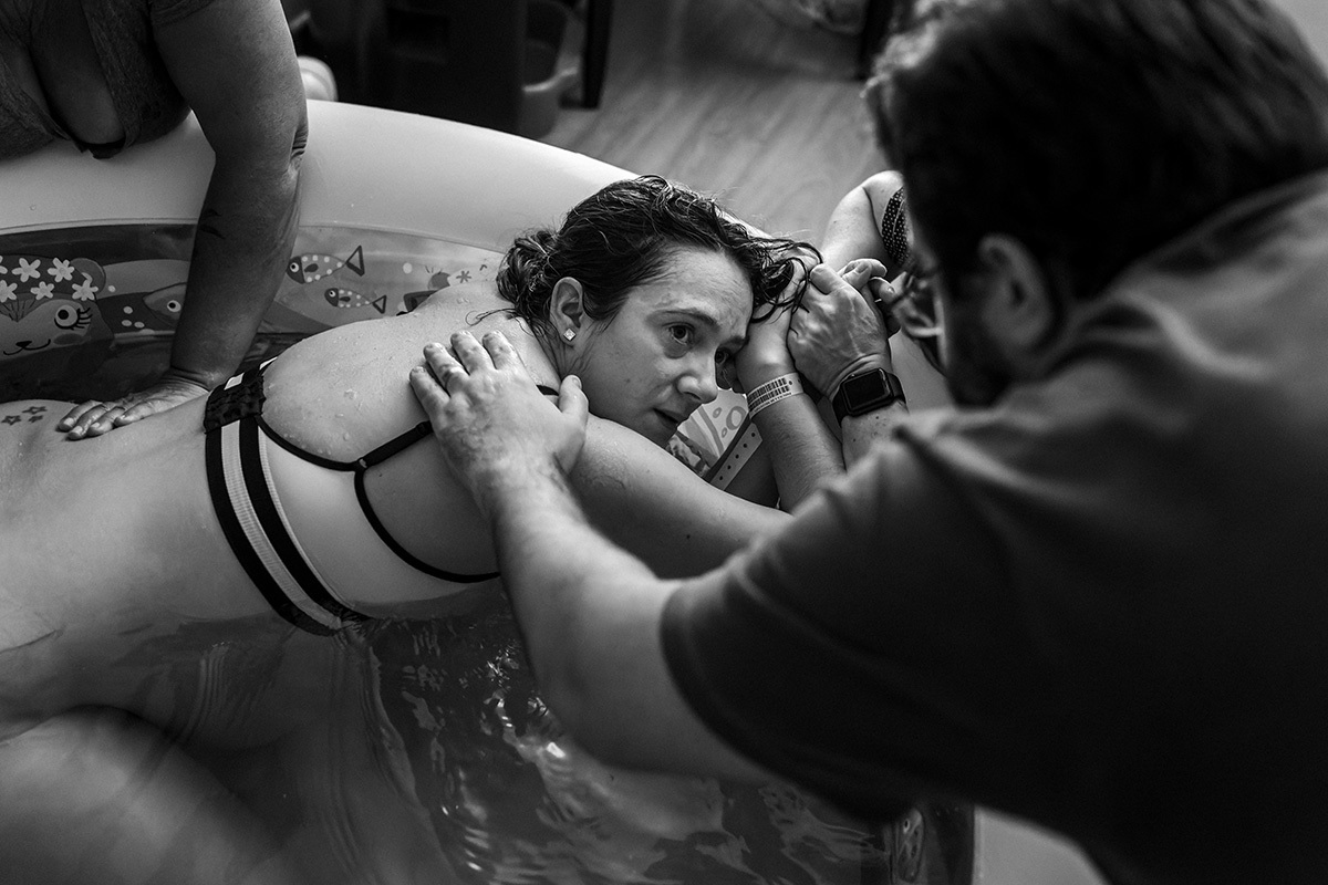 parturiente busca apoio do marido com o olhar durante o trabalho de parto em foto de Adriana Costa