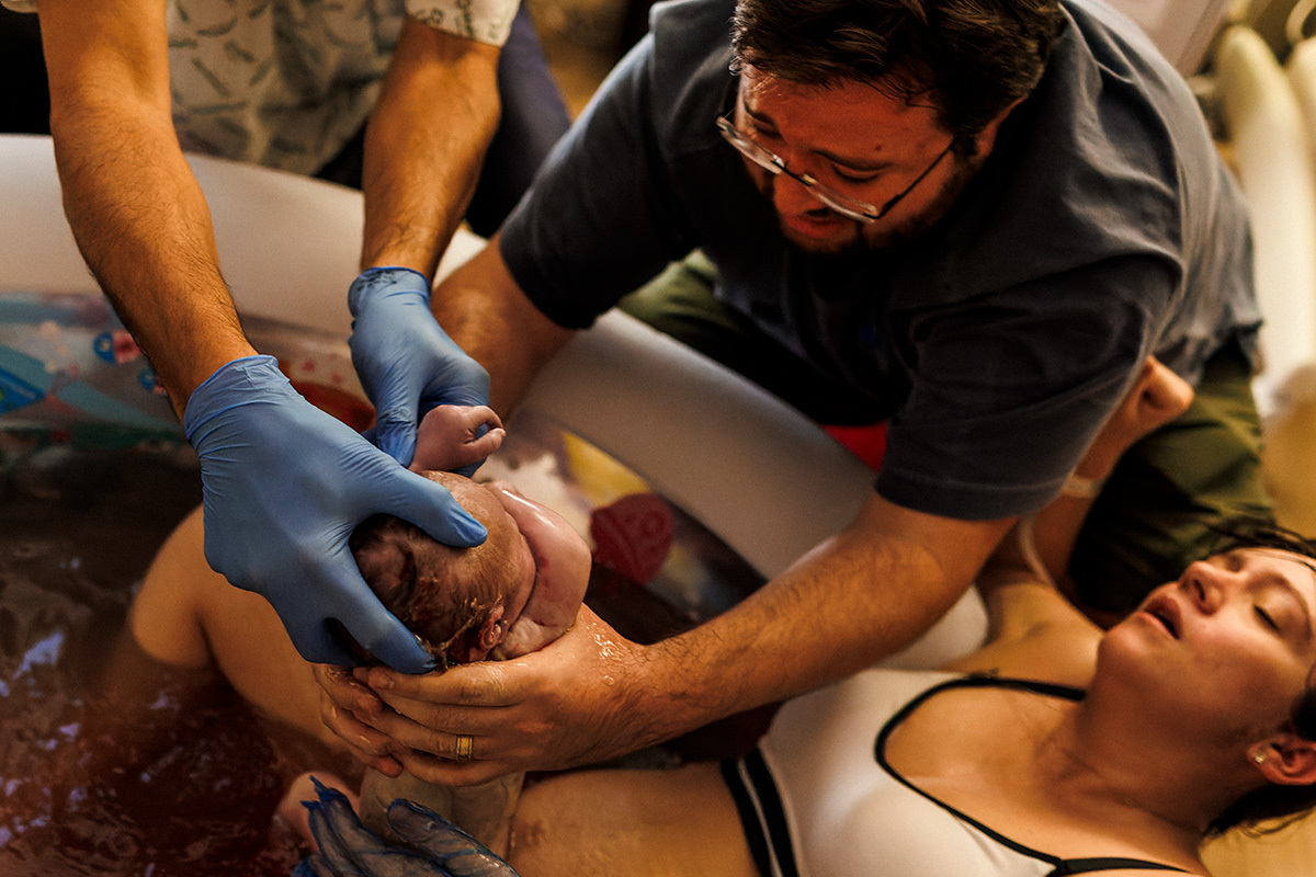 foto de Adriana Costa da emoção do pai ao pegar o seu bebê na água assim que nasceu. 