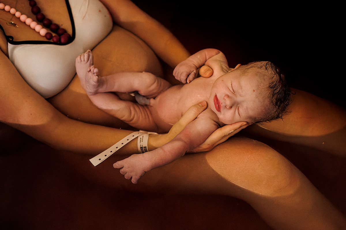 bebê relaxado no colo da mãe ainda na água da banheira onde nasceu