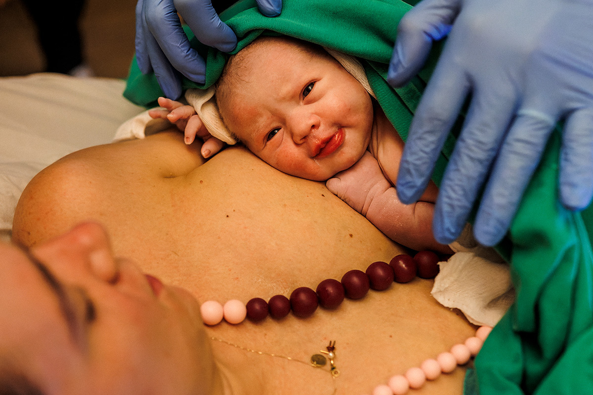 bebê com expressão de sorriso e alegria após o nascimento de parto natural na água em foto de Adriana Costa
