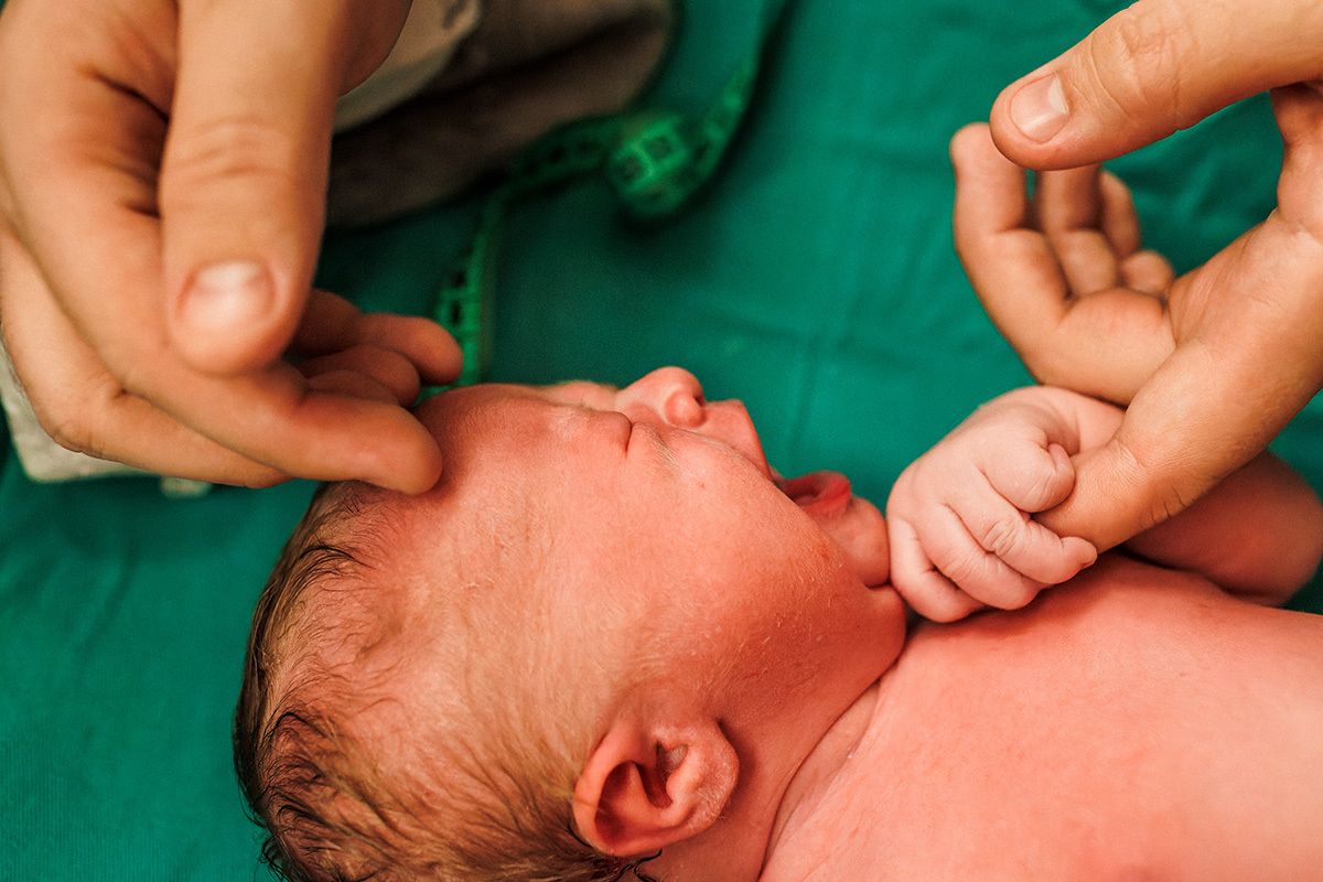 bebê sendo acalmado pelo pai durante os primeiros exames pós parto