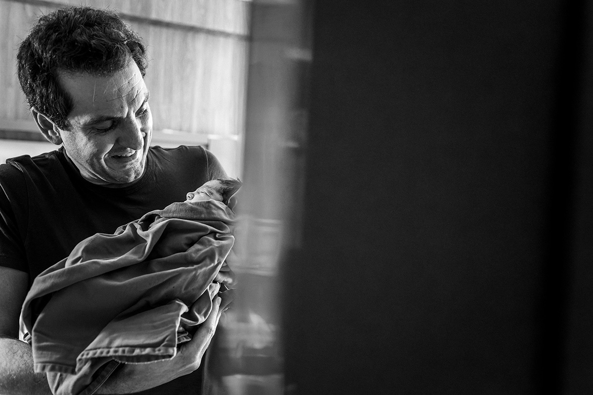 pai segura orgulhoso sua filha que acabou de nascer em foto de Adriana Costa