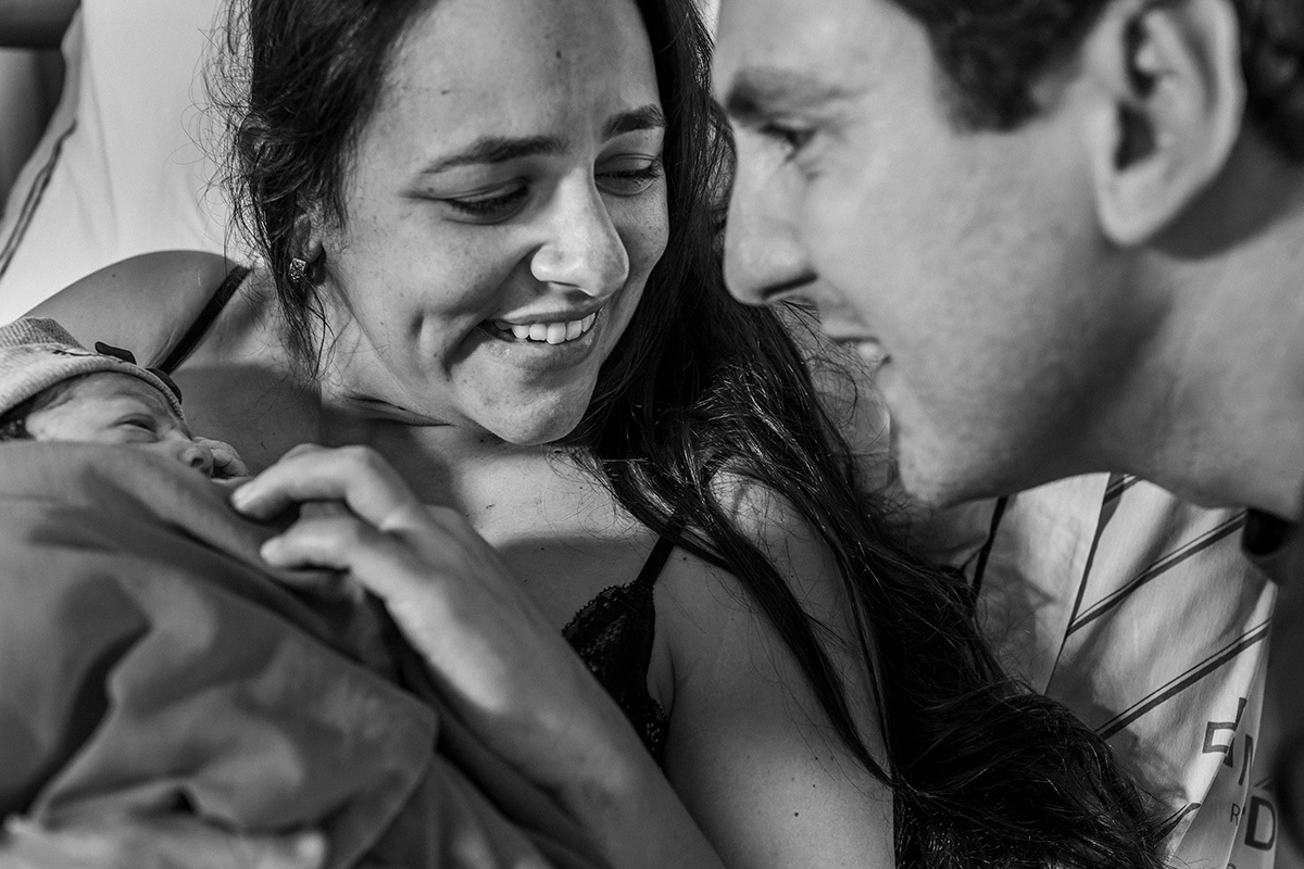 casal olha a filha que acabou de nascer emocionados