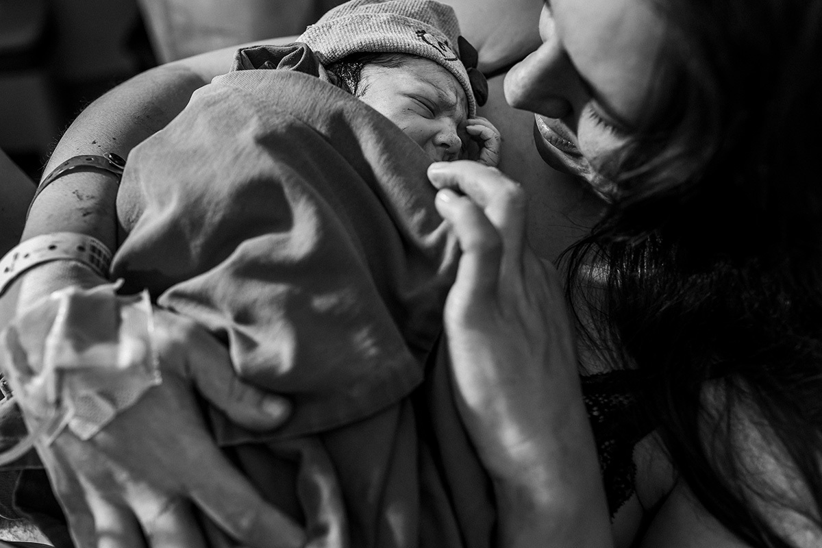 mãe admira a filha em seu colo logo após o nascimento