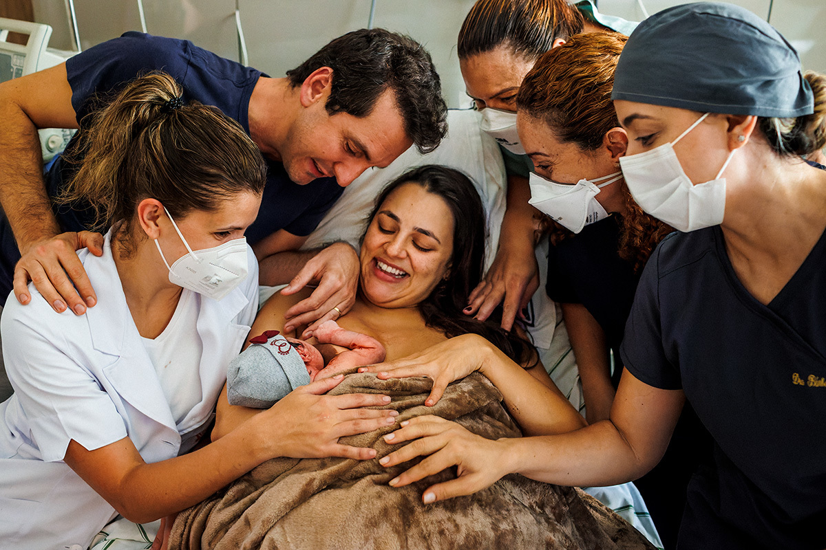 equipe confraterniza o nascimento do bebê ao lado do casal