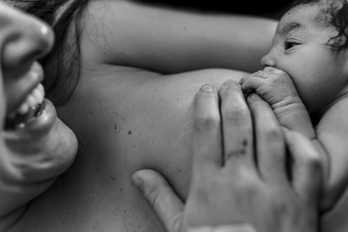 mãe ri emociona durante imprinting de sua filha com ela após o nascimento