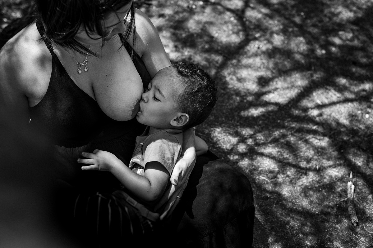 criança amamenta e faz carinho no irmão que está na barriga de sua mãe