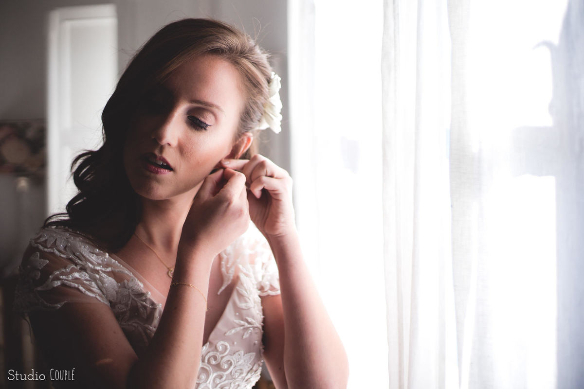 noiva colocando os brincos momentos antes da cerimonia  